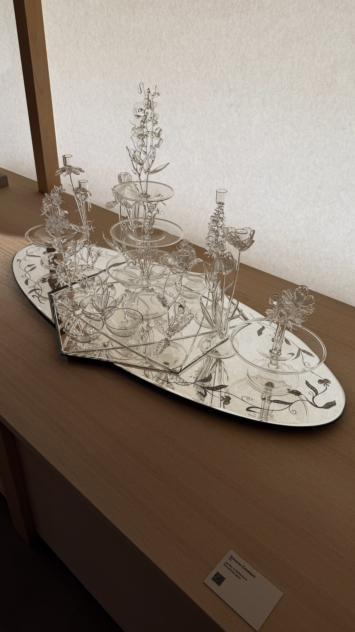 Delicate glass forms on a mirrored surface.