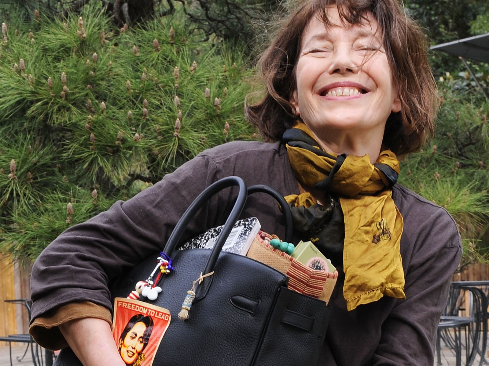 Jane Birkin smiling while holding her personalised Birkin bag.