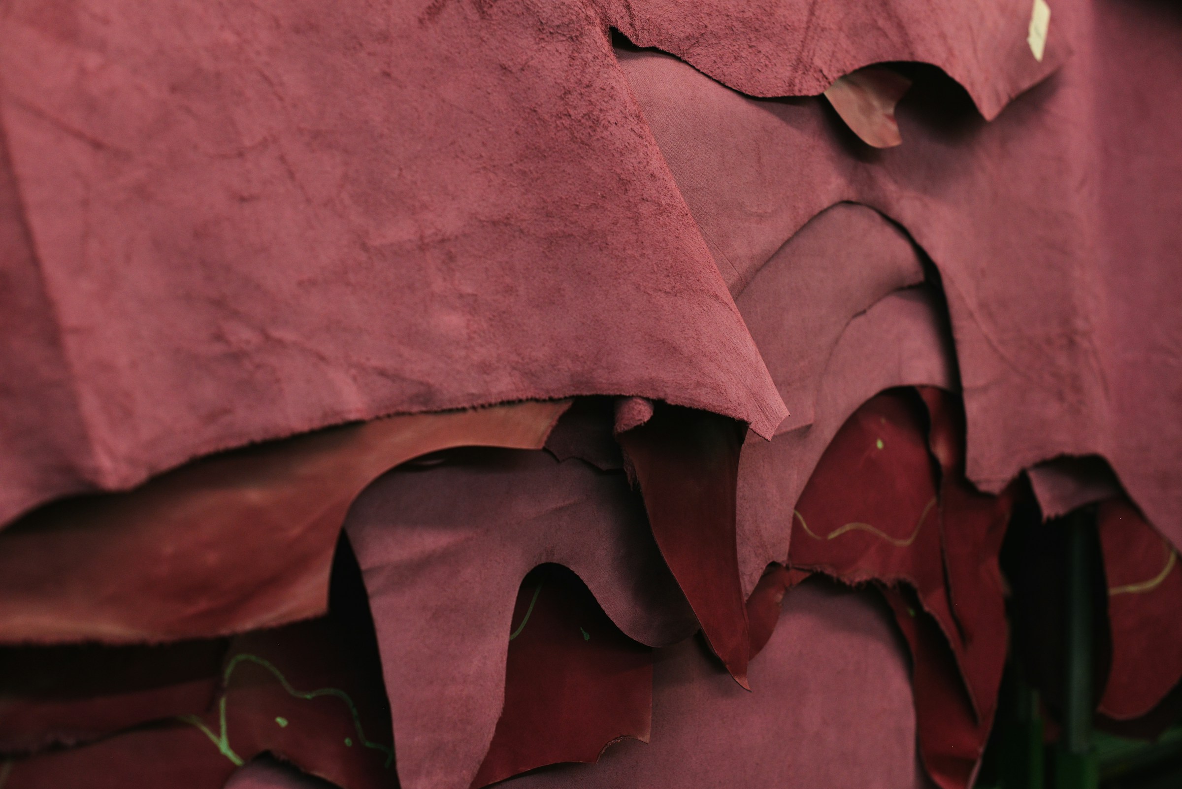 Layers of richly coloured leather revealing the material behind a crafted object.