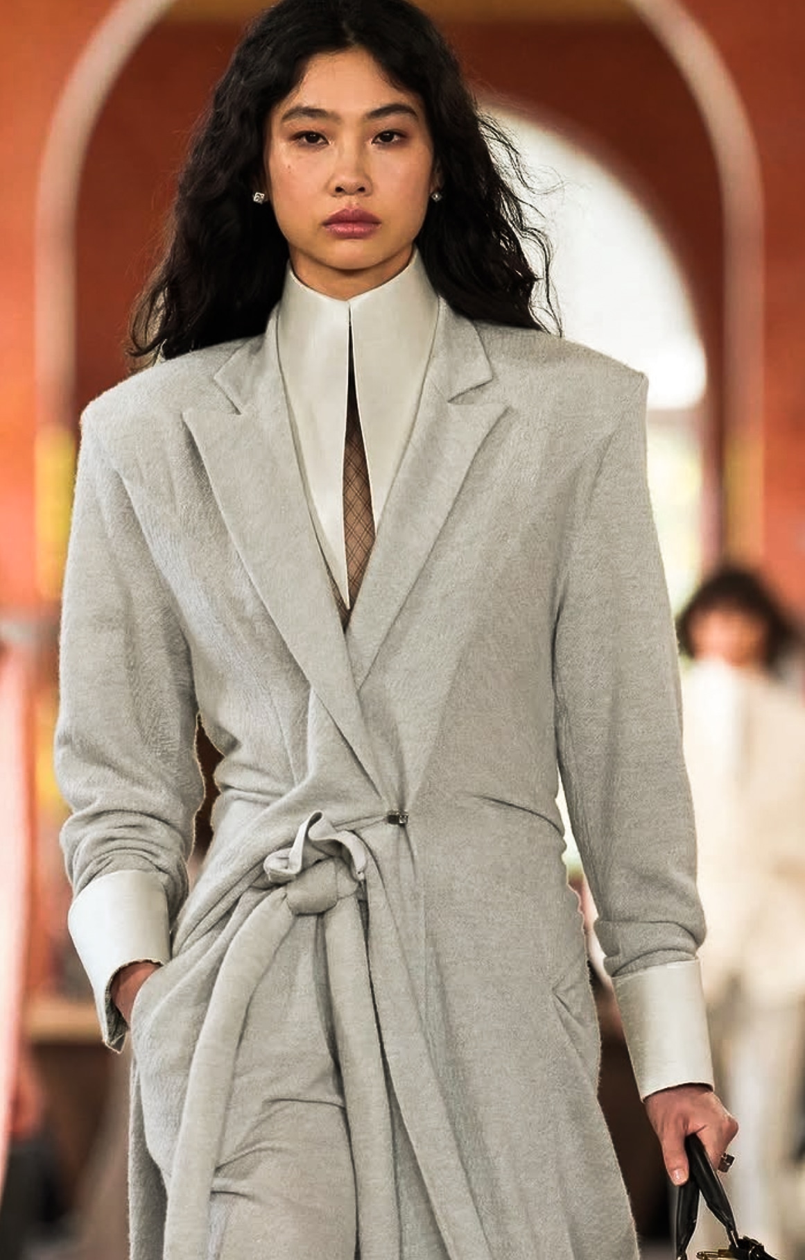 Light grey belted tailoring with a high white collar on a runway.